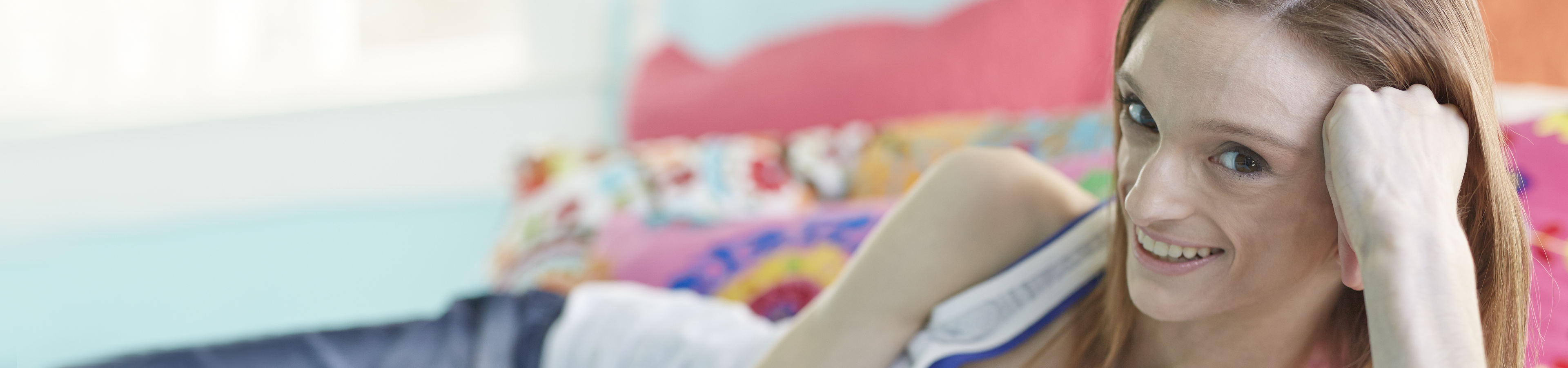 Young woman with GL smiling and sitting on her bed